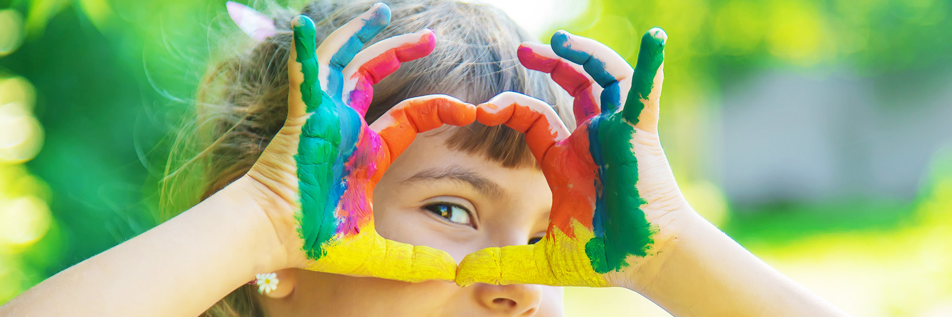 Kind mit bunten Händen formt Herz 